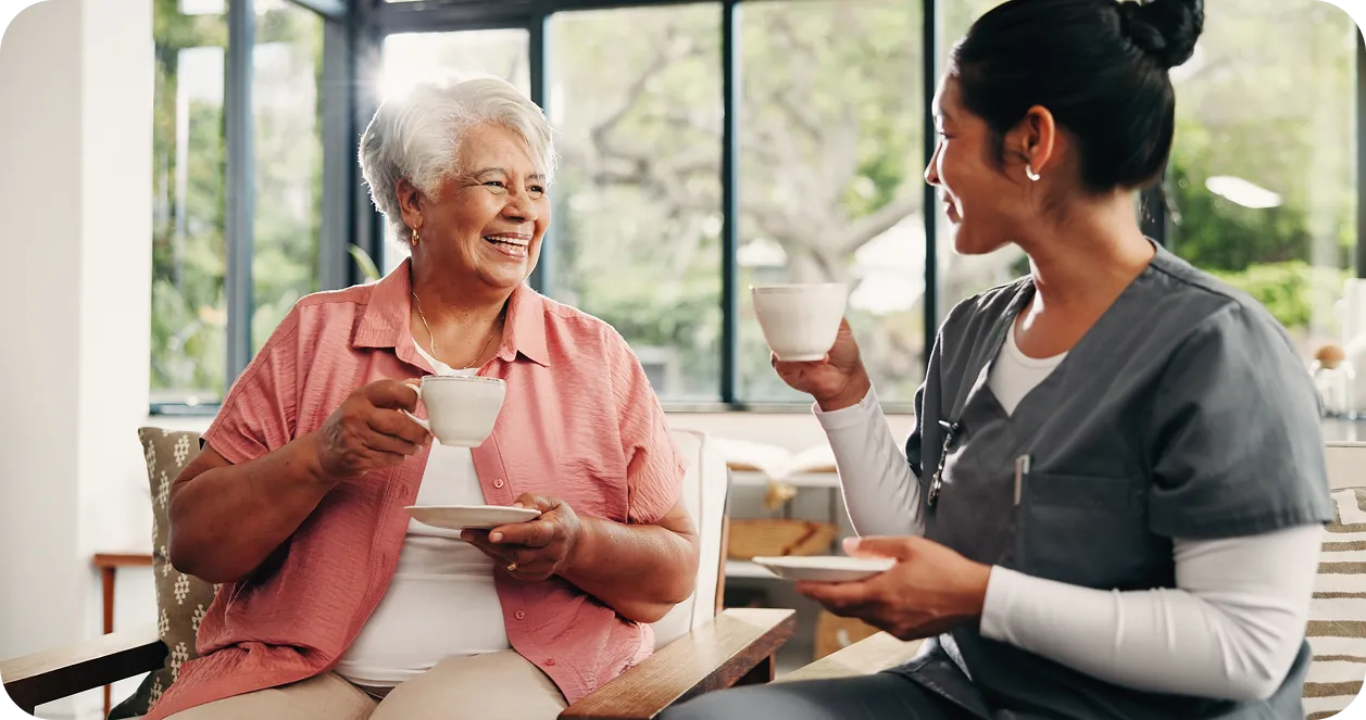 Caregiver sitting with senior client enjoying tea