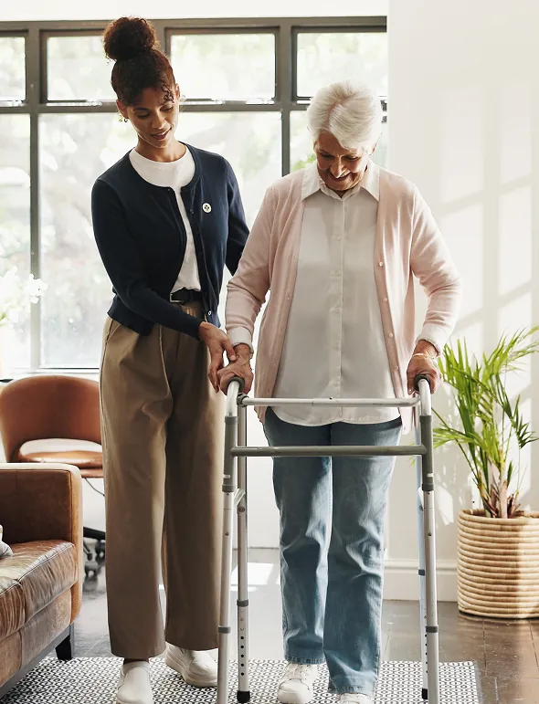 Caregiver assisting elderly woman with walker